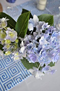 a vase filled with blue and white flowers on top of a table next to candles