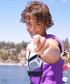 a man pointing at the camera while wearing a purple wet suit