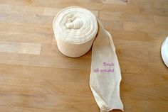 a roll of white yarn sitting on top of a wooden floor next to a pair of scissors