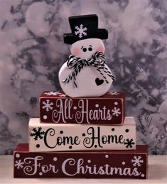 a snowman sitting on top of three stacked books with the words all hearts come home for christmas