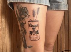 a woman with a tattoo on her leg has a can of beer and a flower