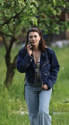 a woman walking in the grass while talking on her cell phone and looking off to the side