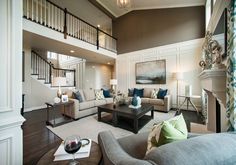 a living room with couches, chairs and a coffee table in front of a staircase