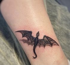 a small black dragon tattoo on the right arm and leg, with wings spread out