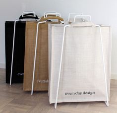 three shopping bags sitting on top of each other in front of a wall with the words everyday design printed on it