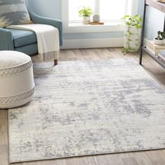 a living room with a blue chair and white rug on the hardwood floor next to a window