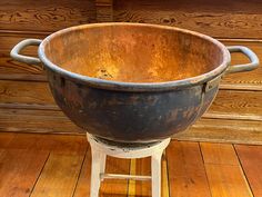 an old metal bowl sitting on top of a wooden floor