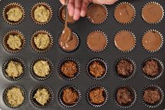 someone is spreading chocolate on top of cupcakes in muffin tins with a spoon