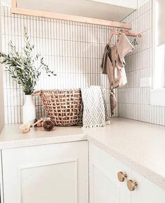 a laundry room with white cabinets and tile backsplash, hanging clothes on the rack