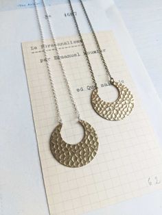 "A horsehoe crescent, in textured brass.  Fine chain is attatched to each point. The pendant measures 1\" 1/4 wide, and 1\" tall.  The chain is silver and nickle free.  Necklace measures 18\" long in total.  Each piece comes beautifully wrapped.  Made in Manchester, UK. Join me on instagram: https://www.instagram.com/themagpiesdaughter" Silver Crescent Brass Necklace, Minimalist Hammered Metal Necklaces, Minimalist Hammered Metal Necklace, Silver Brass Necklace With Moon Charm, Silver Necklace With Moon Charm In Brass, Silver Etched Brass Necklace, Etched Silver Brass Necklace, Large Pendant Necklace, Modern Jewellery