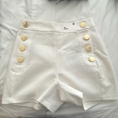 Elevate Your Wardrobe With These Stunning High-Rise Shorts That Exude Old Money Elegance. Crafted With A Premium Fabric Blend, These Shorts Feature A Flattering High-Waisted Silhouette And Eye-Catching Gold Button Detailing That Adds A Touch Of Sophistication. Designed To Flatter Your Figure, The High-Rise Waist Cinches At The Smallest Part Of Your Midsection, Creating A Sleek And Streamlined Look. The Fabric Is Soft, Breathable, And Slightly Stretchy For All-Day Comfort. Perfect For Dressy Casu Buttons Outfit, Classy Shorts, Elegant Shorts, Button Shorts, White High Waisted Shorts, Button Outfit, Simple Tee, Simple Tees, Shorts White