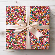 a gift wrapped in sprinkles with a white bow on it's side