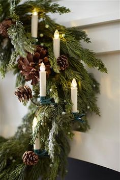 a christmas wreath with lit candles and pine cones