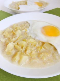 an egg is on top of some food in a white bowl with green tablecloth