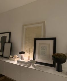 a shelf with pictures and other items on top of it in a room that has white walls