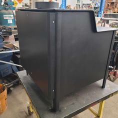 a large black box sitting on top of a metal shelf in a factory room with other equipment