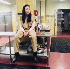 a woman sitting on top of a metal table in a room with red flooring