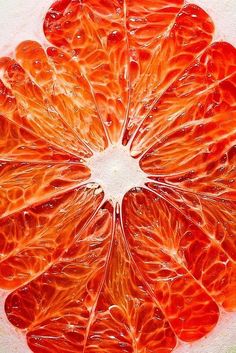 an orange cut in half sitting on top of a white surface with water droplets all over it