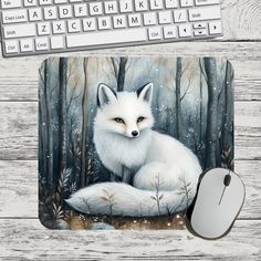 a mouse pad with an image of a white fox in the woods on it next to a keyboard