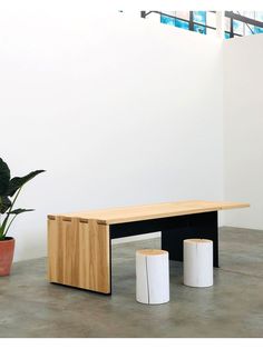 a wooden bench sitting next to two white vases on top of a cement floor