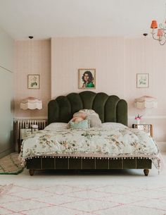 a bedroom with pink walls and a green headboard on a bed in front of a chandelier