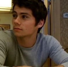 a young man sitting at a table with a plate of food in front of him