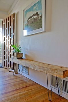 a long wooden table sitting on top of a hard wood floor next to a window