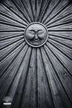 a wooden door with a face carved into the front and side panel, in black and white