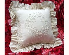 a white pillow sitting on top of a bed covered in red and pink sheets with ruffled edges