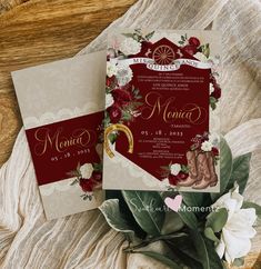 two red and white wedding cards sitting on top of a wooden table next to flowers