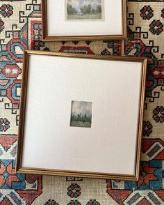 two framed pictures sitting on top of a rug next to each other, one is empty