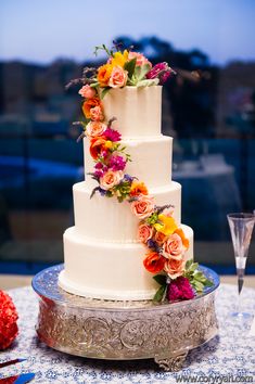 a three tiered white cake with colorful flowers on top