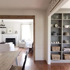 a dining room table and chairs in front of a book shelf with baskets on it