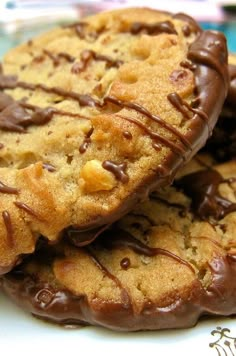 three chocolate chip cookies on a plate with one being drizzled with chocolate