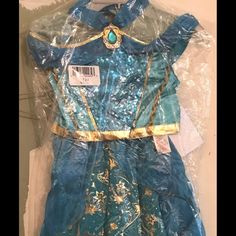 a blue dress with gold details on the collar and shoulders is wrapped up in plastic