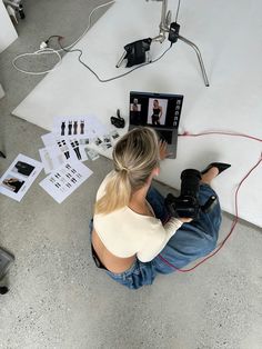 a woman is sitting on the floor with her camera and recording equipment in front of her