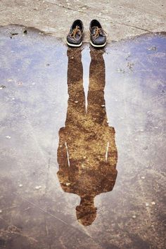 a pair of shoes that are sitting on the ground in front of a puddle with water