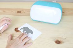 someone cutting out a bear silhouette on a piece of paper with a blue and white machine