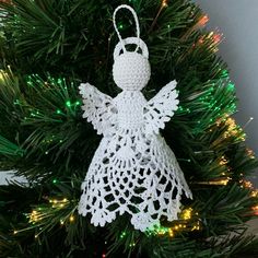 a crocheted angel ornament hanging from a christmas tree