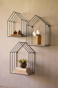 three metal shelves with plants and vases on them, hanging from the side of a wall