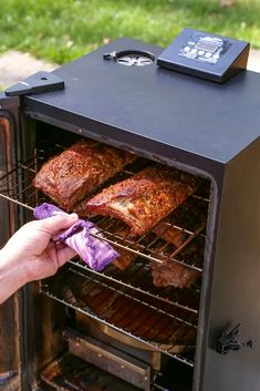 a person is pulling some food out of an outdoor smoker with it's door open