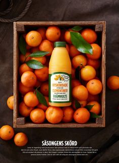 an orange juice in a wooden box surrounded by tangerines