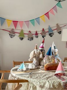 two stuffed animals are sitting at a table with party hats on it's head