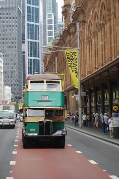 a green and yellow bus driving down a street next to tall buildings in the city