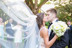 a bride and groom kissing in front of their wedding party