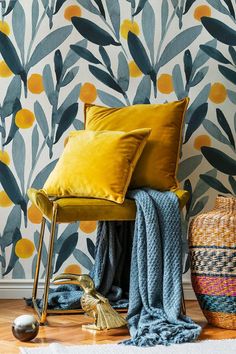 a yellow chair sitting in front of a wallpaper with leaves and plants on it