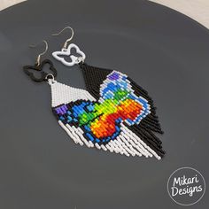 a pair of beaded bird earrings on top of a black plate next to scissors