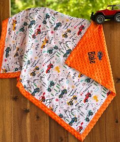 two bibs with cars and trucks on them, one has an orange trim around the edges