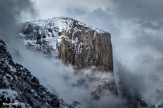 the mountain is covered in snow and clouds