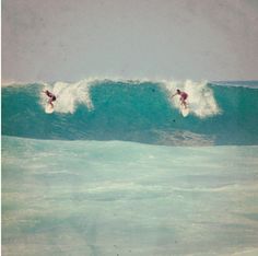 two surfers are riding the same wave in the ocean, one is on his surfboard